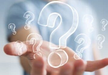 Businessman on blurred background holding hand drawn question marks