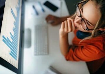 Young women reading data from paper and internet